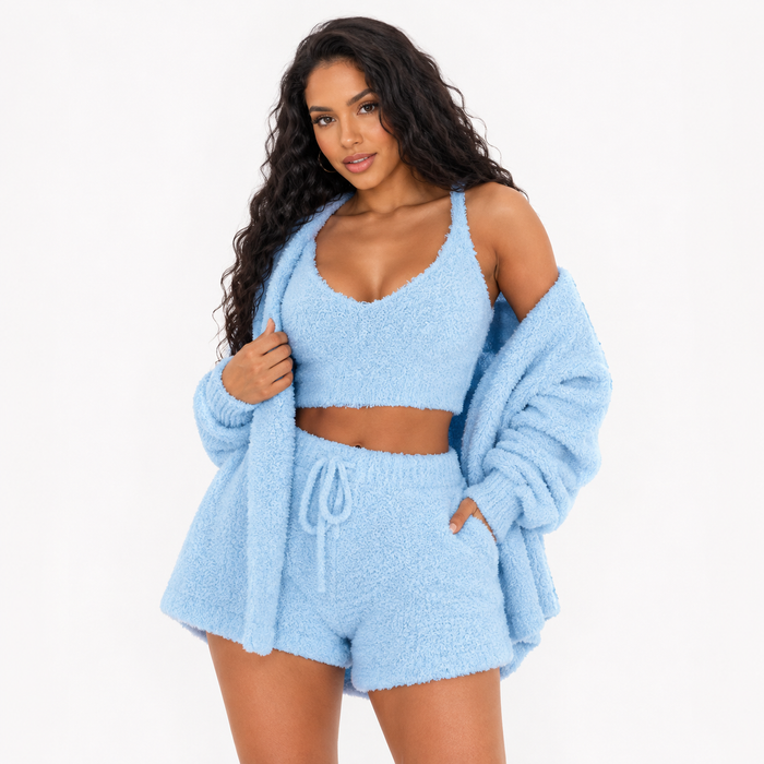 Women's three piece velvet lounge set in blue with cardigan, crop top and drawstring shorts on a clean white studio backdrop.