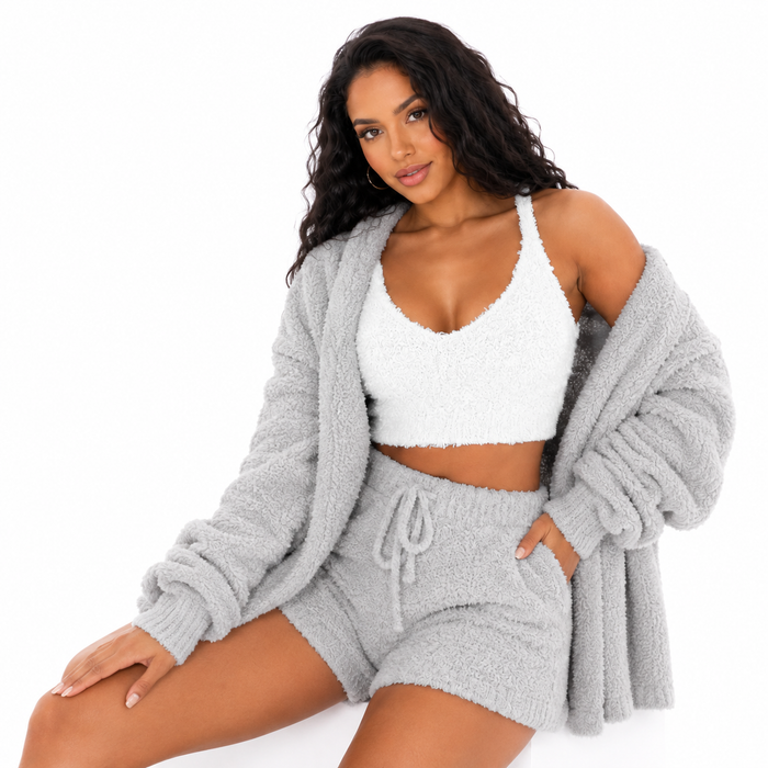 Blue women's three piece velvet lounge set with crop top, cardigan and drawstring shorts shown in a seated clean studio pose.