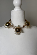 Golden Bloom statement necklace set with high-shine gold floral details, pearlized petal accents, a chunky chain, and matching earrings.