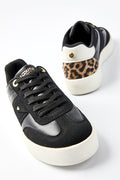 The Ampton Low-Profile Trainer in Black/Leopard features chunky white soles, black laces, and a leopard print heel. One shoe is shown from the front, while the other displays the back and side views, highlighting its classic trainer design.