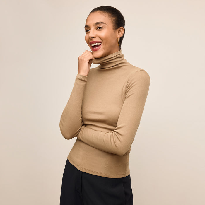 Woman wearing a beige turtleneck sweater against a beige background