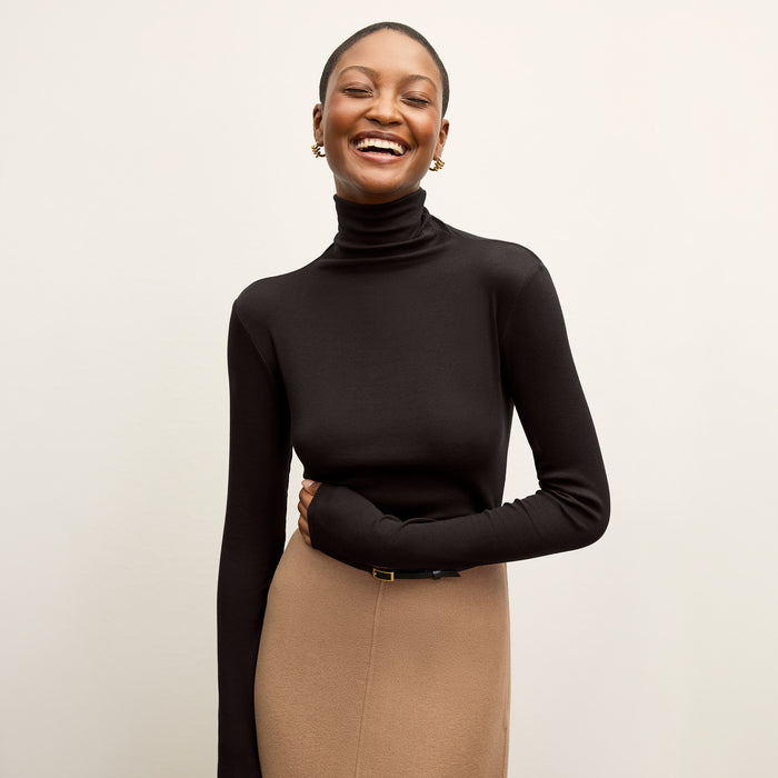 Front image of a woman standing wearing the axam top in black | Lead