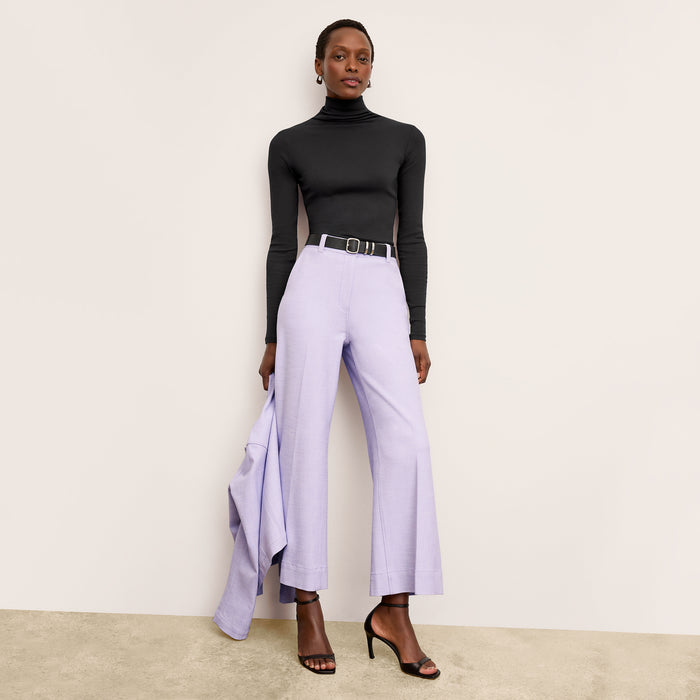 Front image of a woman standing wearing the axam top in black