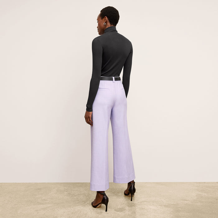 Back image of a woman standing wearing the axam top in black