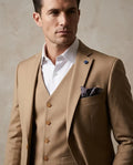 Man wearing a brown suit with a white shirt against a neutral background