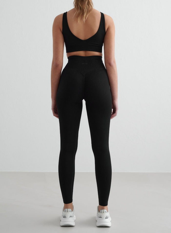 Nainen takaapäin yllään mustat aim'n Shape Seamless Tights -trikoot. [S - 175 cm]