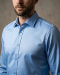 Man wearing a light blue dress shirt against a neutral background