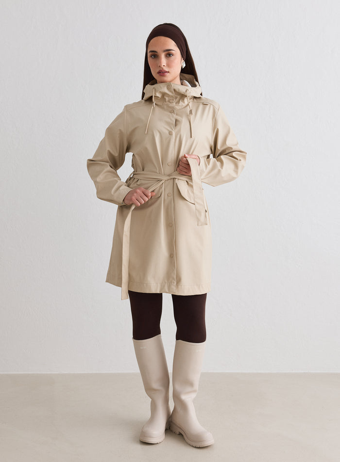Nainen yllään aim'n cafe-au-lait Rain Jacket, jossa on vyötärövyö ja huppu [M-174cm]