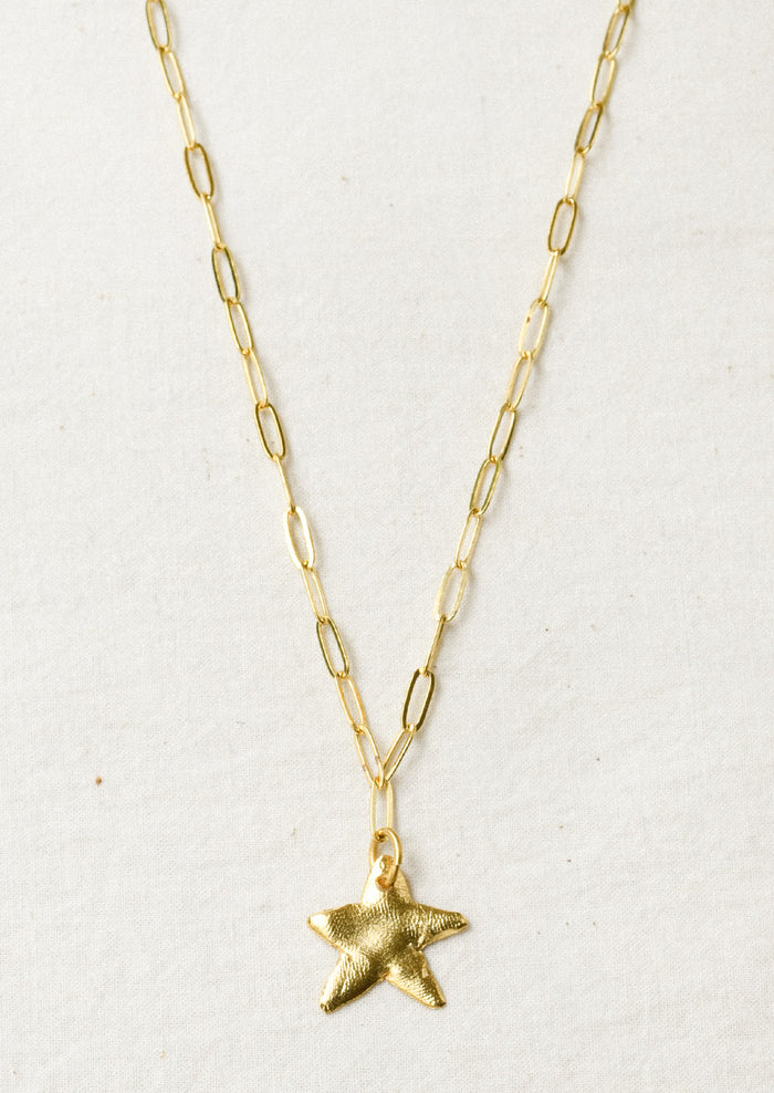 A gold paperclip chain necklace with a large star pendant.