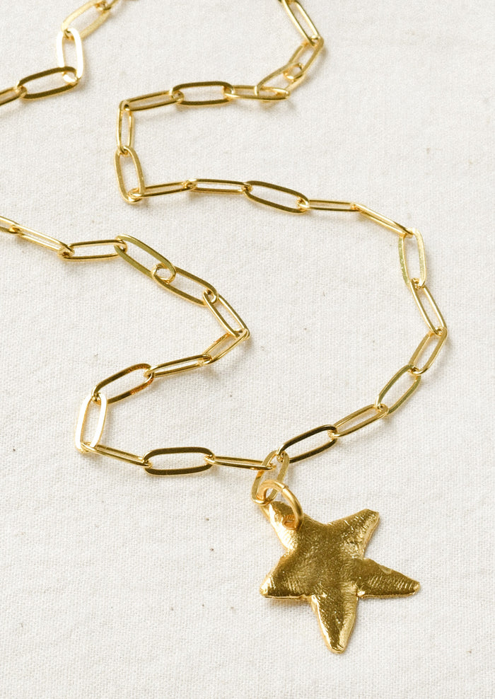 A gold paperclip chain necklace with a large star pendant.