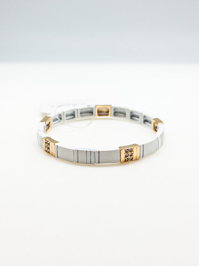 A sleek white bracelet with gold accents and crystal details, designed to fit most wrists.