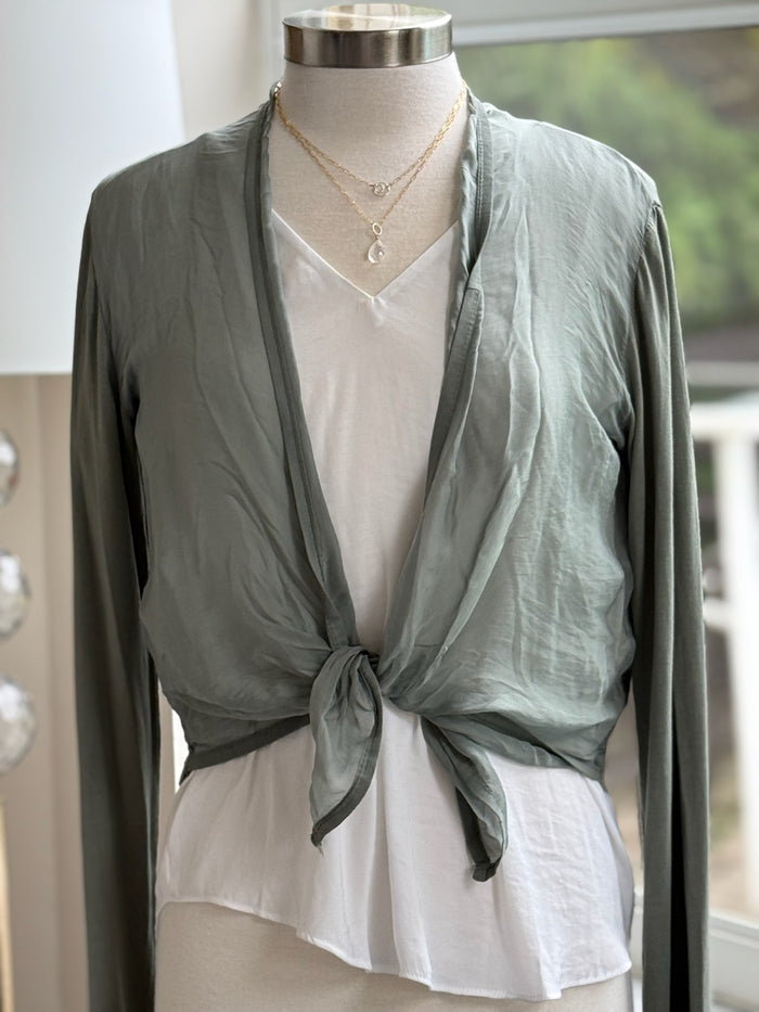 A green olive silk cardigan with a tie-front, displayed on a mannequin with  a necklace.