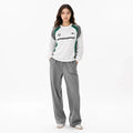 Professional female model wearing White color block raglan sleeve sweatshirt on white background, full face visible, square image.