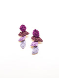 Pair of textured drop earrings with layered purple, mauve, and lilac stacked shapes on a white background.