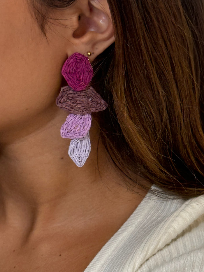 Pair of textured drop earrings with layered purple, mauve, and lilac stacked shapes on a model