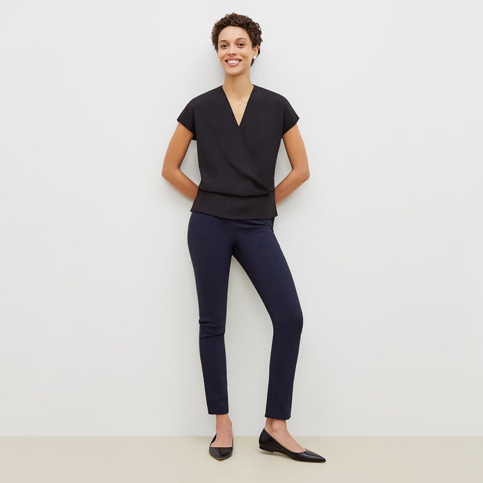 Front image of a woman standing wearing the foster pant in dark navy