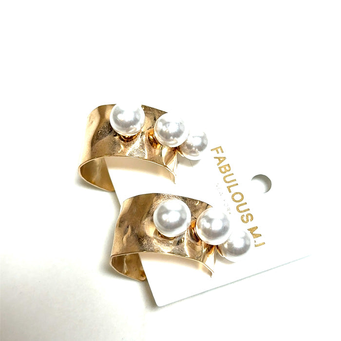 Gold statement earrings with a hammered curved cuff shape and oversized pearl accents.