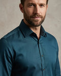 Man wearing a teal shirt against a neutral background