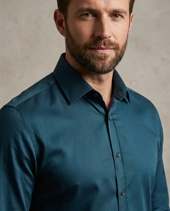Man wearing a teal shirt against a neutral background