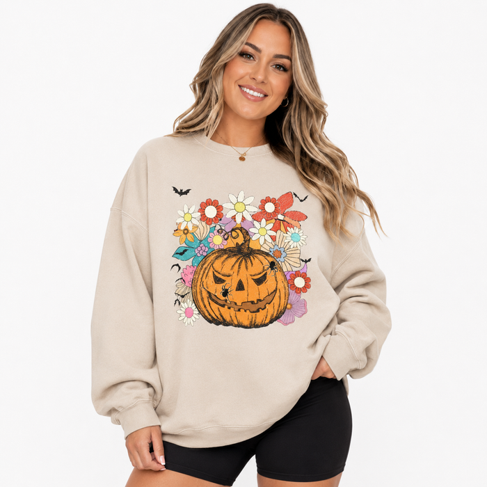 Woman wearing beige Halloween pumpkin floral sweatshirt with jack-o-lantern graphic on a clean white studio background.