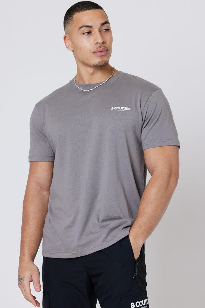 A man models the Hartfield 3-Pack Regular Cotton T-Shirt in grey, featuring a crew neck and B COUTURE signature chest branding, styled with black pants and a chain necklace against a plain background.