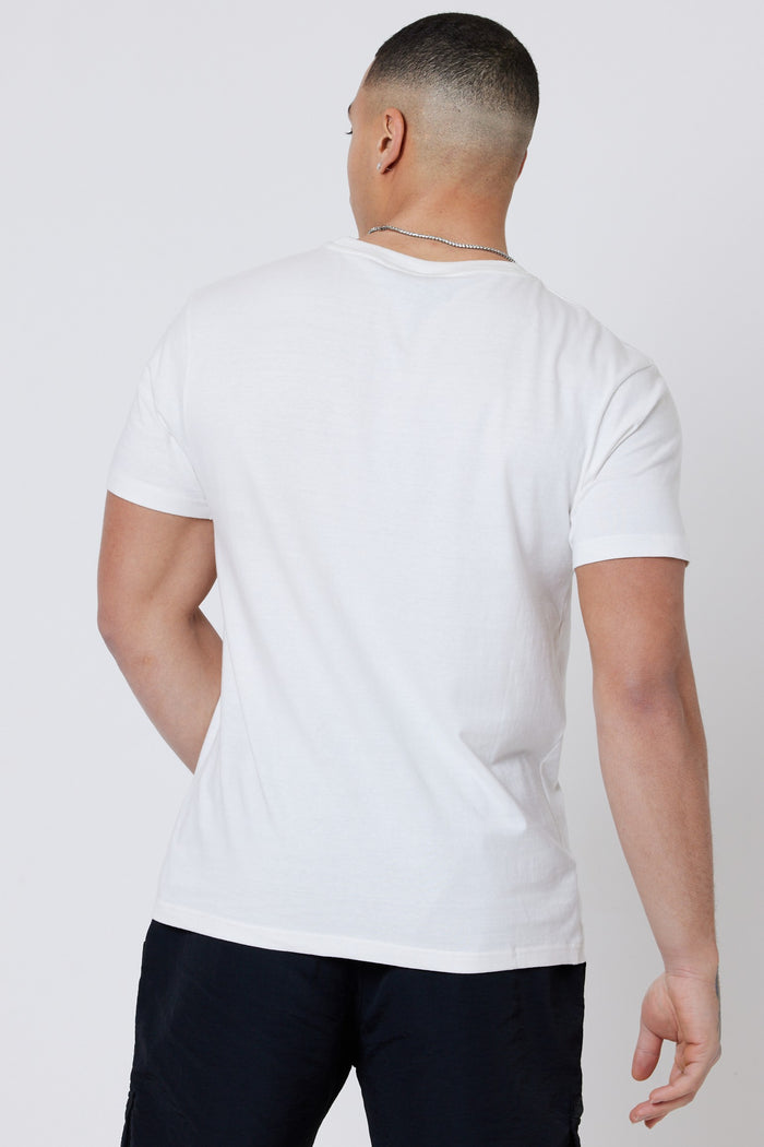 A man with short hair stands with his back to the camera, wearing a Hartfield 3-Pack Regular Cotton T-Shirt in cream, black shorts, and a silver necklace against a plain light background.