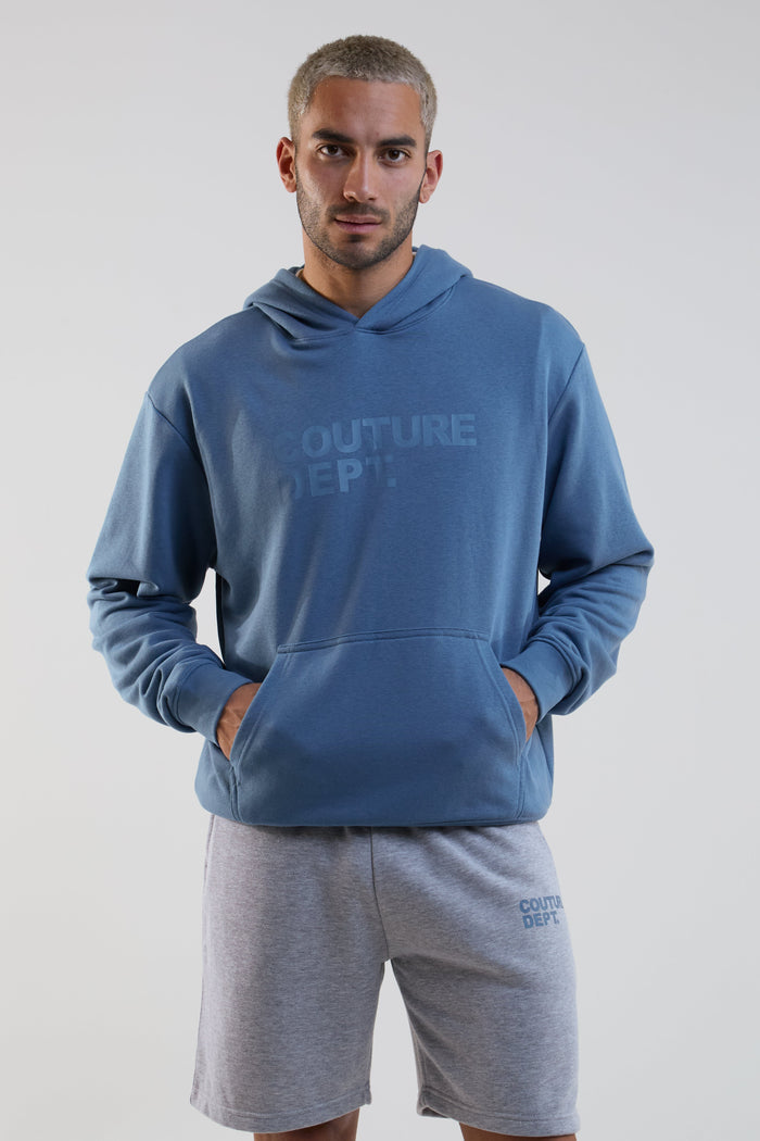 Man wearing a blue hoodie and gray shorts with 'Couture Dept.' branding on a white background