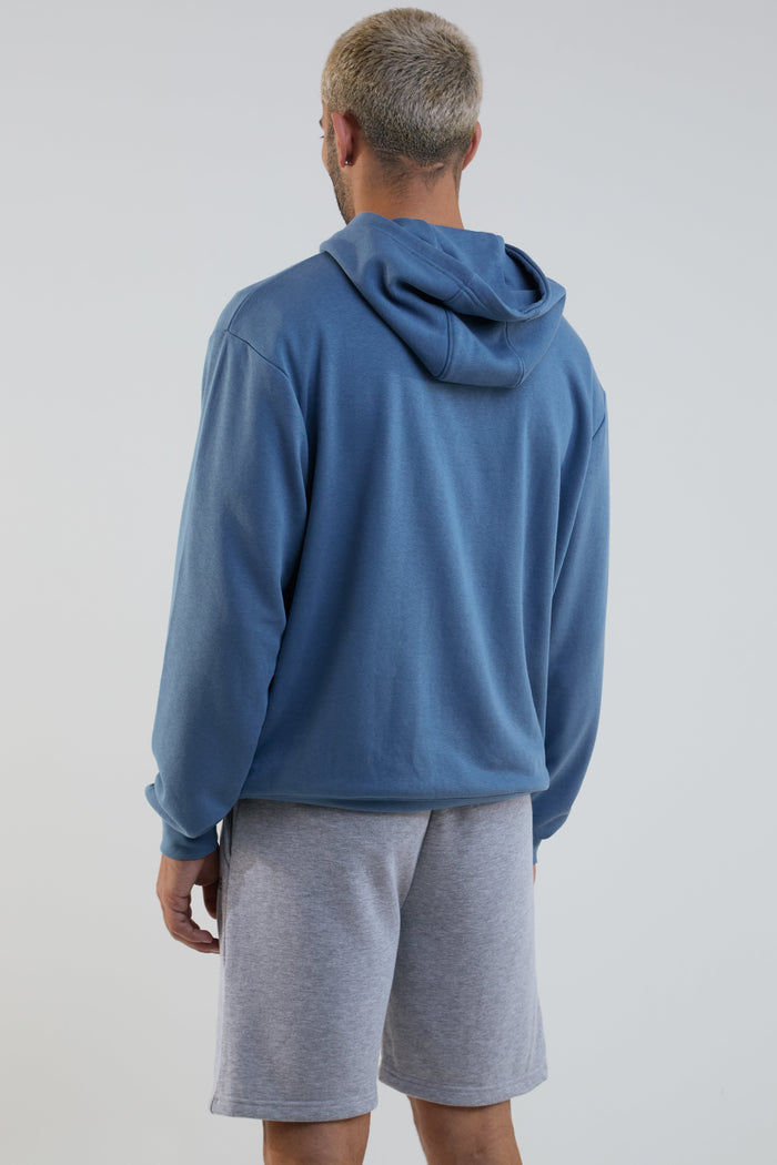 Person wearing a blue hoodie and gray shorts on a plain background