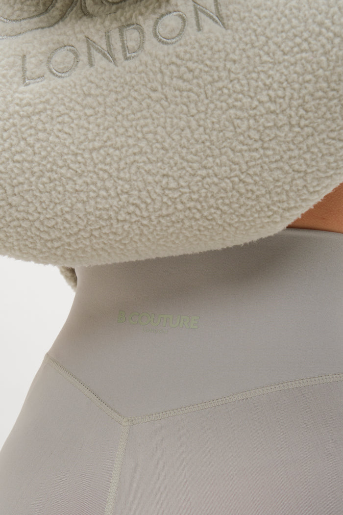 Close-up of a person in the Isla Sherpa Hoodie & Leggings Set in teal, featuring a plush fleece hoodie with LONDON embroidery and form-fitting leggings. The cosy, oversized hoodie stands out against the plain white background.