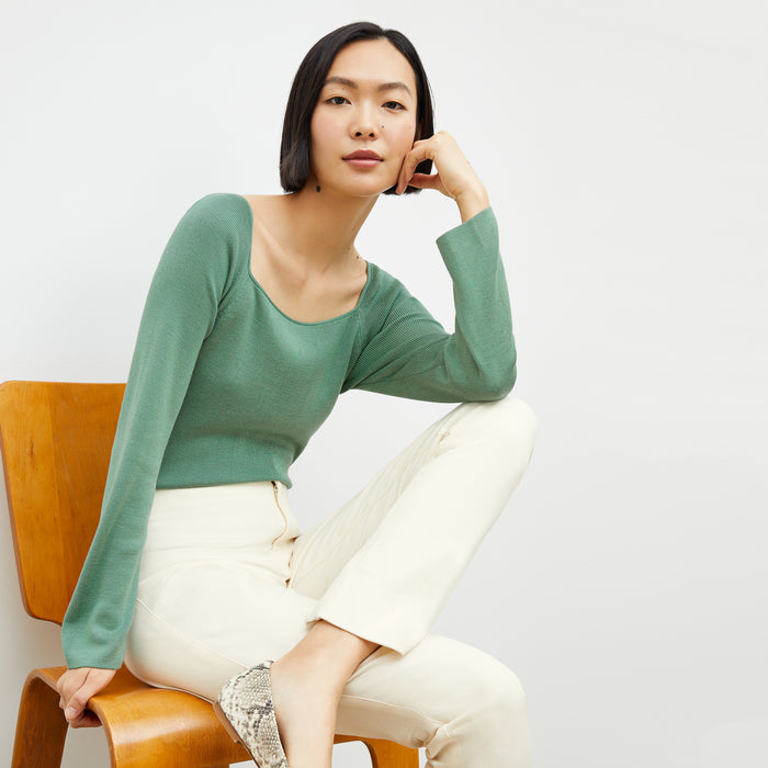 Front image of a woman sitting wearing the joya top in spring green | Lead