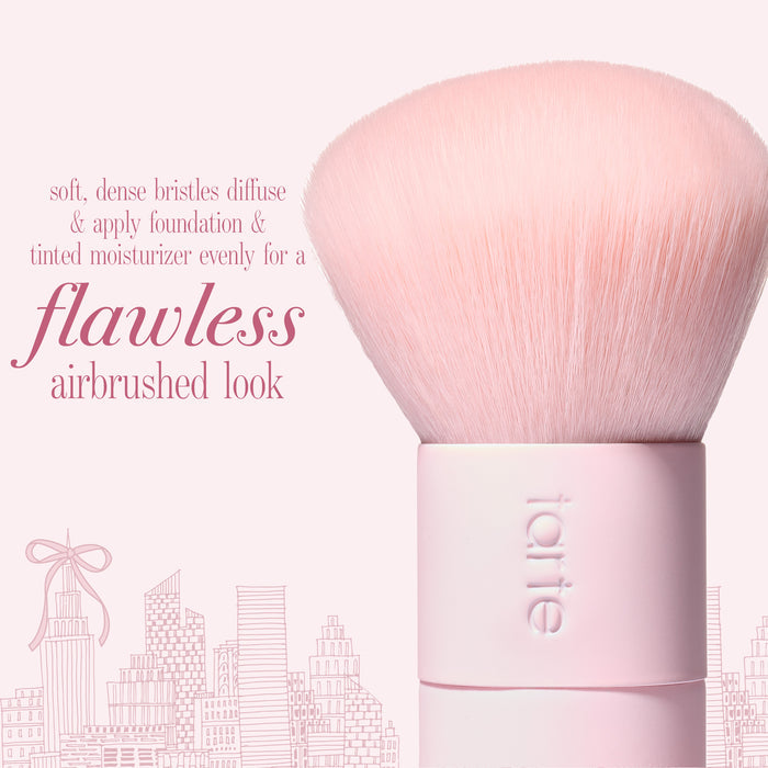 A light pink makeup brush with dense soft bristles and a pink handle, shown on a pink background with text  'flawless airbrushed look'