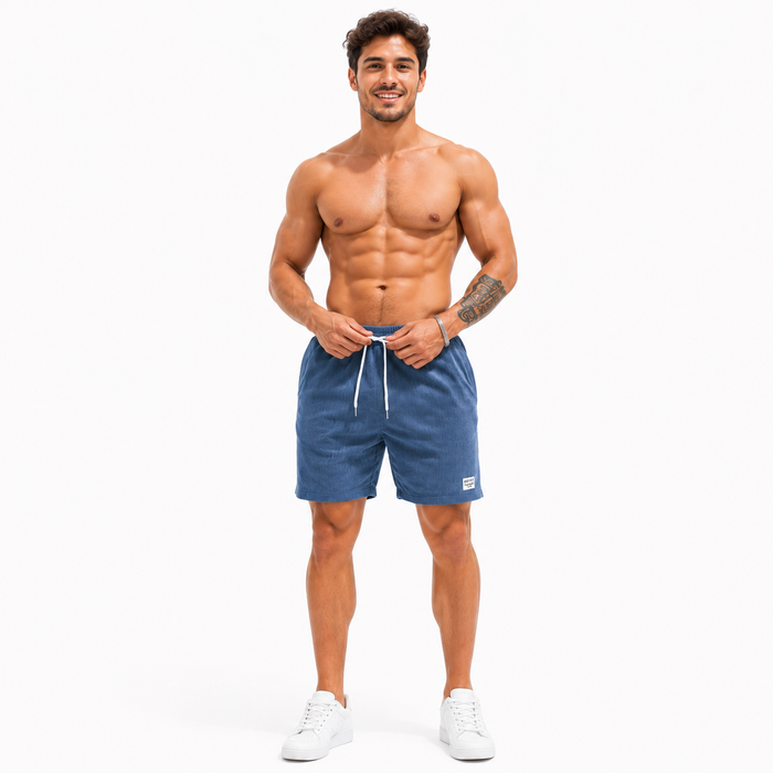 Men's blue corduroy shorts shown front facing while a male model adjusts the drawstring waist on a clean white studio background.