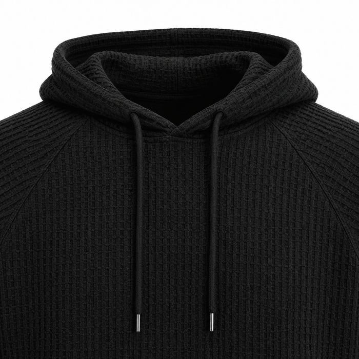Black waffle knit hoodie close-up showing hood, drawstrings and raglan seam construction.