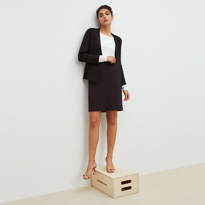 Front image of a woman standing wearing the Noho skirt in black. | Lead