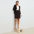 Front image of a woman standing wearing the Noho skirt in black. | Lead