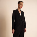 Woman wearing a black suit against a beige background | Lead