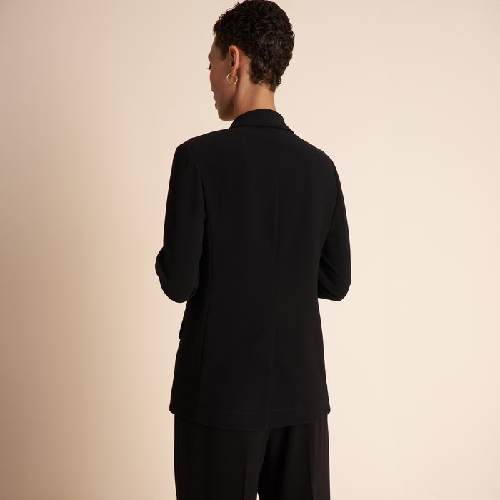 Person wearing a black suit on a beige background