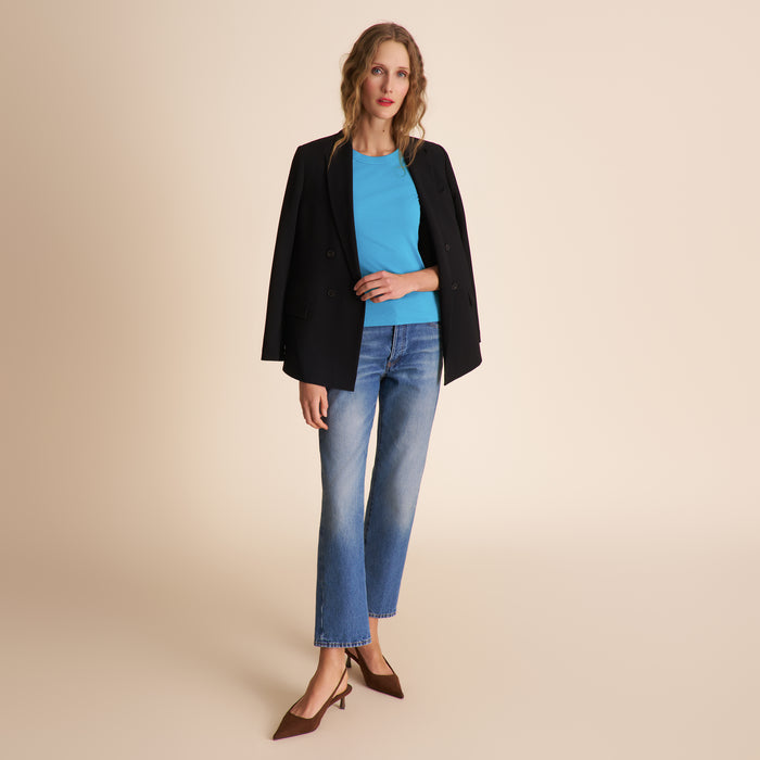 Women in black blazer with aqua blue top and blue jeans