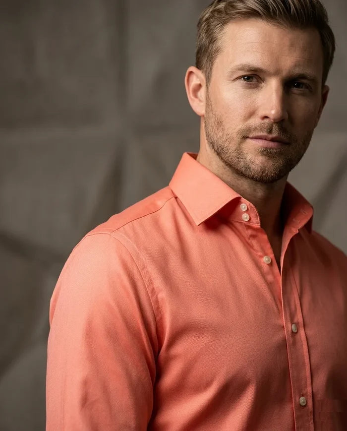 Man wearing a coral-colored shirt against a neutral background