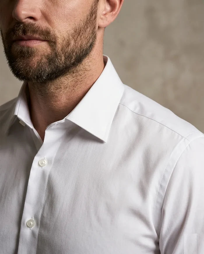 Close-up of a man wearing a white dress shirt against a neutral background