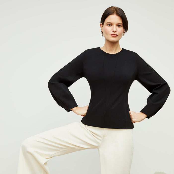 Front image of a woman standing wearing the rashida top in black | Lead