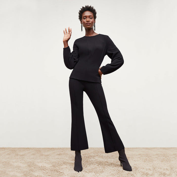 Front image of a woman standing wearing the rashida top in black