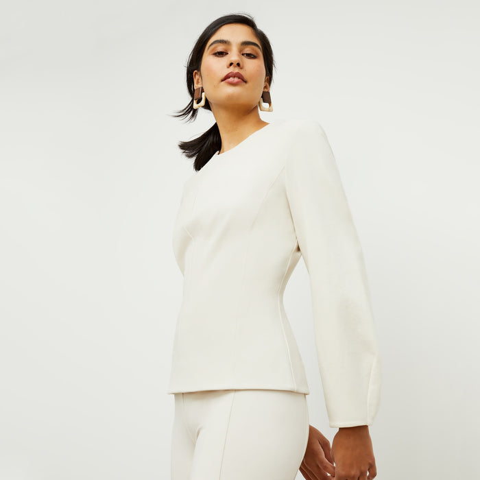 Side image of a woman standing wearing the rashida top in pearl