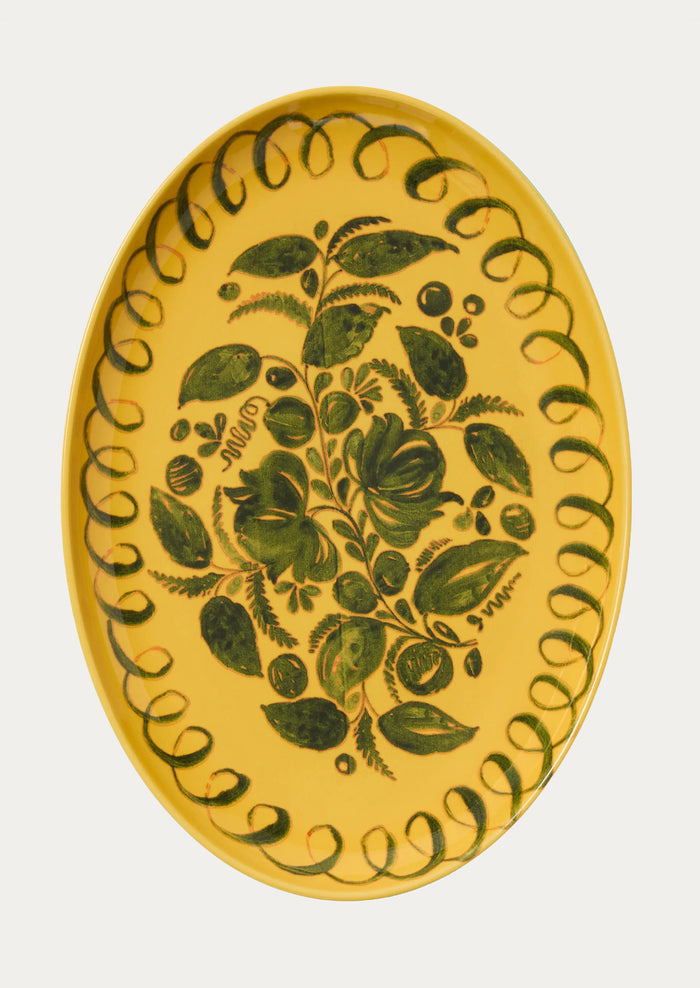 Decorative plate with green leaf pattern on a yellow background