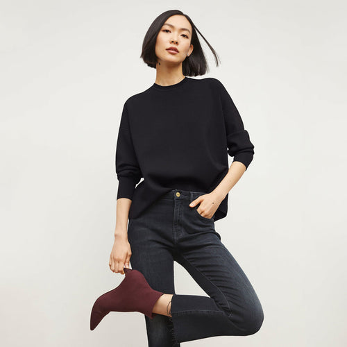 Front image of a woman standing wearing the FRAME Denim Le Crop Slim Bootcut Raw Edge Jean in Marcella | Grid Hover