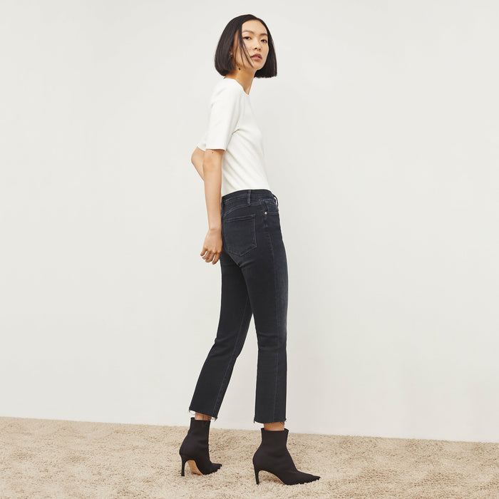 Back image of a woman standing wearing the FRAME Denim Le Crop Slim Bootcut Raw Edge Jean in Marcella
