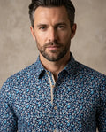 Man wearing a blue patterned shirt against a beige background