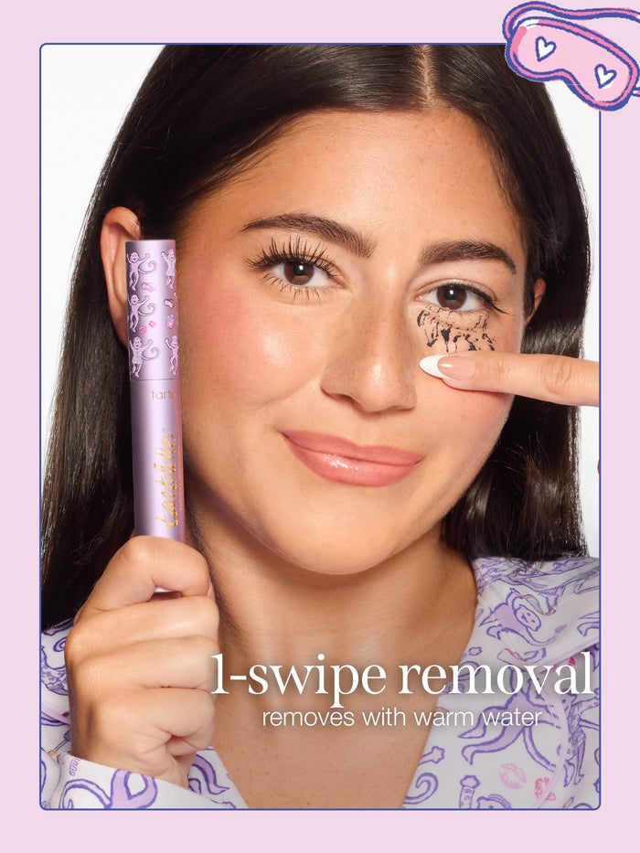 A woman removing tarte cosmetics x roller rabbit collaboration tartelette tubing mascara with limited edition cap with text reading '1-swipe removal' and 'removes with warm water.'