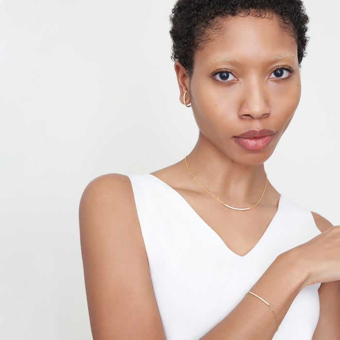 Front image of a woman standing wearing the Thread Bracelet in Yellow Gold