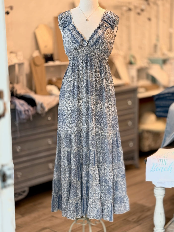 A blue and ivory paisley print maxi dress with ruffled cap sleeves and a smocked waist on a mannequin.